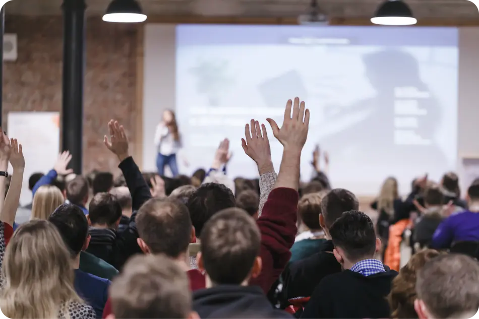 Assemblée levant les mains lors d'une conférence professionnelle